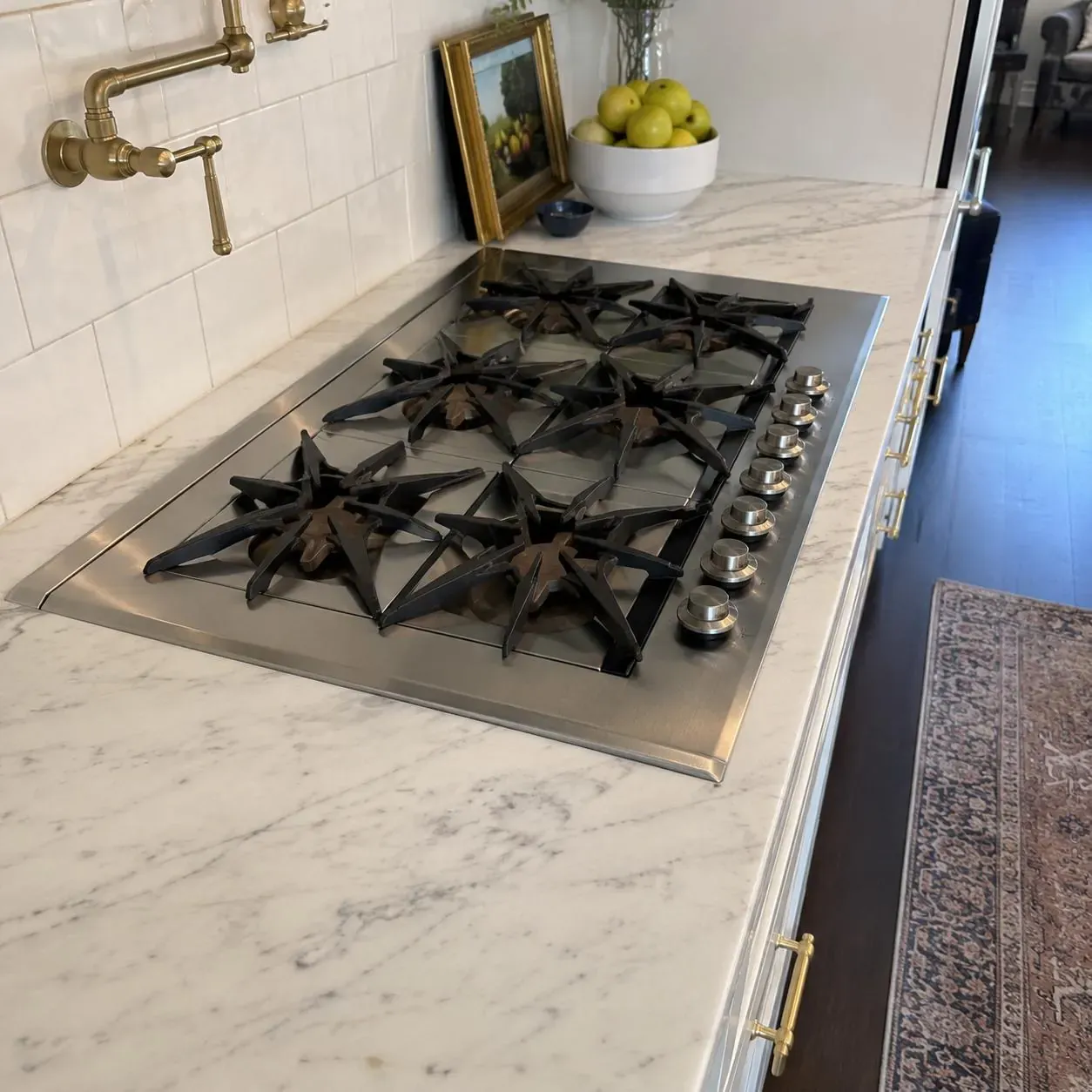 Stainless gas cooktop with star-shaped burners on a marble countertop