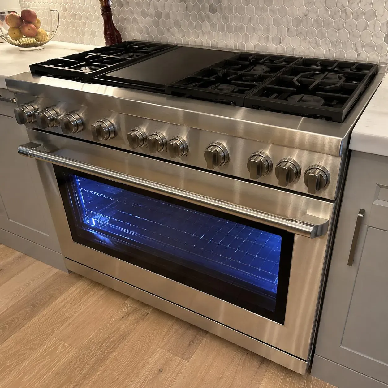 Professional stainless dual-fuel range with a blue-glowing oven