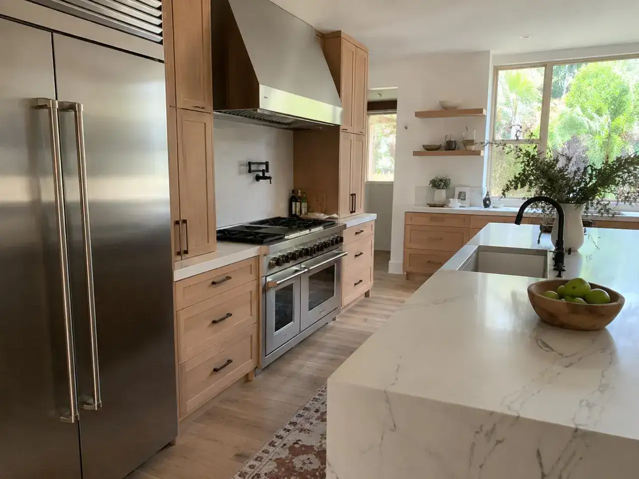 Bright luxury kitchen with a built-in stainless column refrigerator and double wall ovens in oak cabinetry