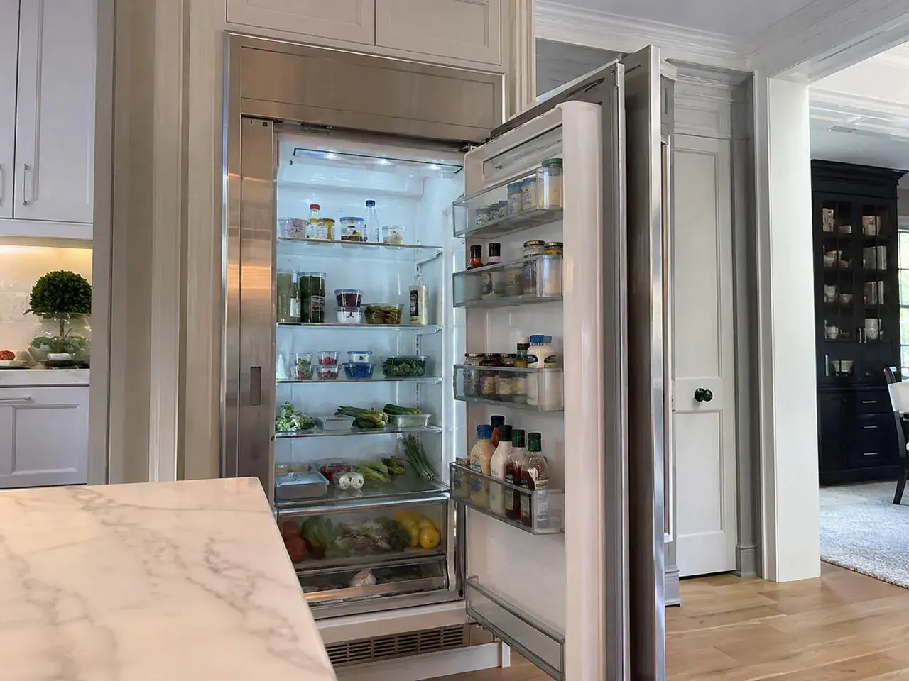 Open built-in column refrigerator stocked with fresh food in a luxury kitchen